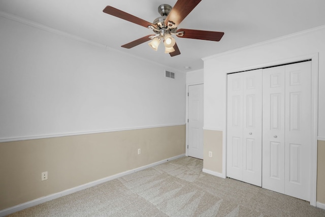 unfurnished bedroom featuring light carpet, ornamental molding, a closet, and ceiling fan