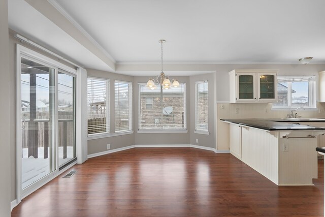 kitchen featuring dark hardwood / wood-style floors, white cabinets, hanging light fixtures, a tray ceiling, and an inviting chandelier