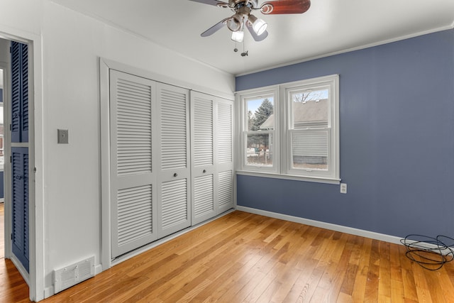 unfurnished bedroom featuring crown molding, ceiling fan, hardwood / wood-style floors, and a closet