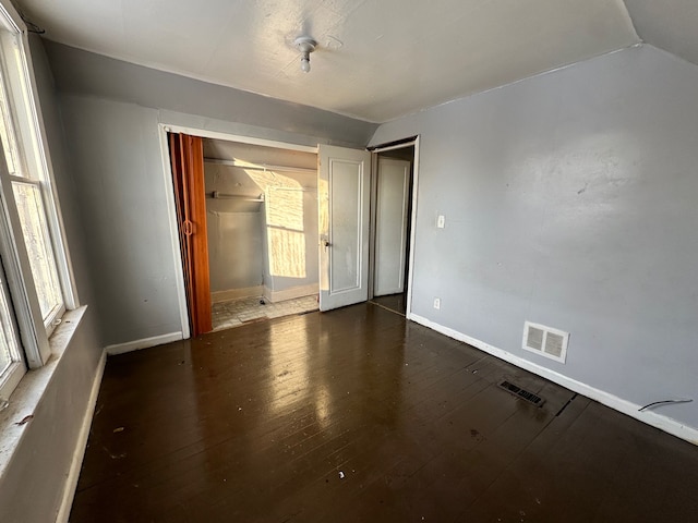 unfurnished bedroom with dark hardwood / wood-style flooring, vaulted ceiling, and a closet