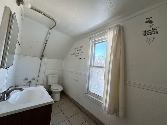 bathroom with tile patterned flooring, vanity, lofted ceiling, and toilet