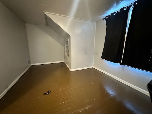 bonus room featuring dark hardwood / wood-style floors and built in shelves