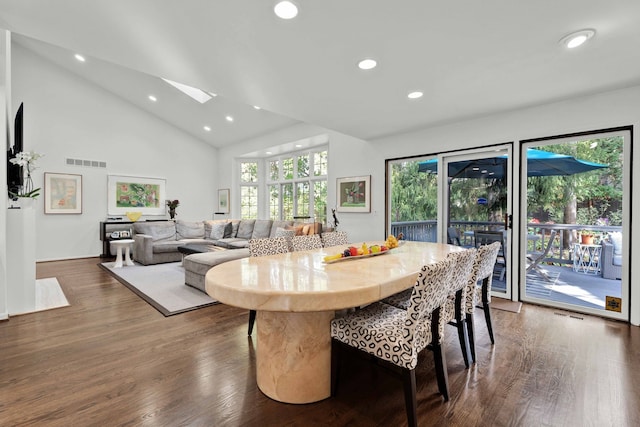 dining space featuring dark wood-type flooring, high vaulted ceiling, and a skylight