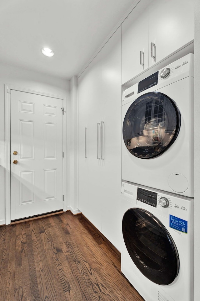 clothes washing area featuring dark wood-type flooring, cabinets, and stacked washing maching and dryer