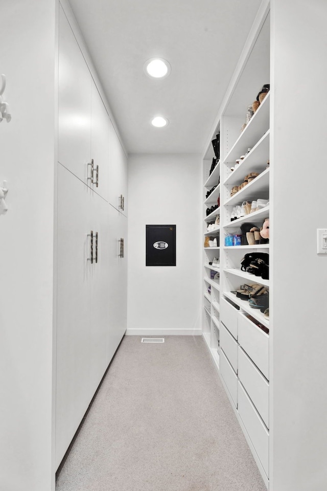 walk in closet featuring light colored carpet