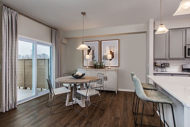 dining space with baseboards and dark wood finished floors