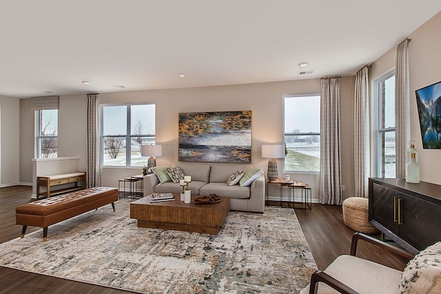 living area with dark wood finished floors, a healthy amount of sunlight, visible vents, and baseboards