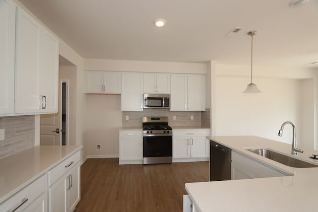 kitchen featuring white cabinets, a sink, light countertops, stainless steel appliances, and tasteful backsplash