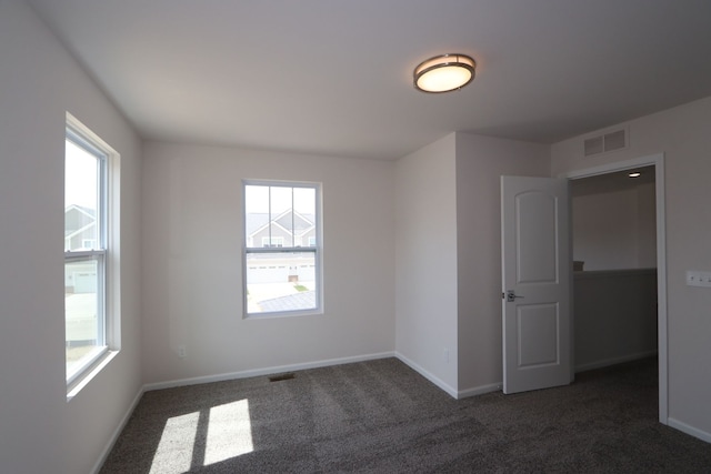 unfurnished room with visible vents, carpet flooring, and plenty of natural light