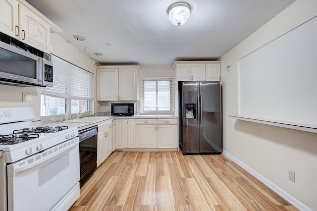 kitchen with sink, black appliances, and light hardwood / wood-style floors