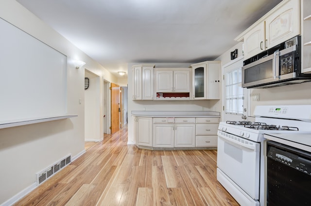 kitchen with white cabinetry, black dishwasher, white range with gas cooktop, and light hardwood / wood-style flooring