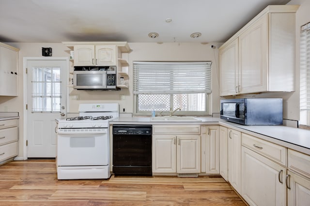 kitchen featuring sink, white range with gas stovetop, light wood-type flooring, dishwasher, and a wealth of natural light