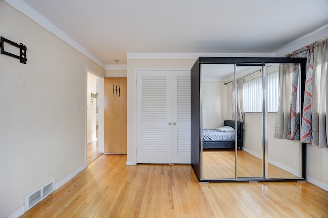 bedroom featuring crown molding and light wood-type flooring