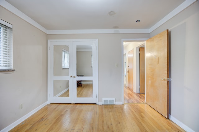 unfurnished bedroom featuring a closet, french doors, and light wood-type flooring