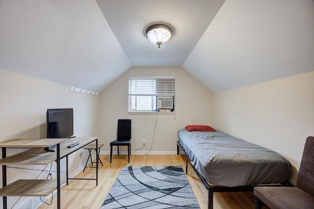 bedroom with cooling unit, light hardwood / wood-style flooring, and vaulted ceiling