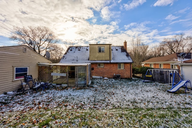 snow covered house featuring a playground and central air condition unit