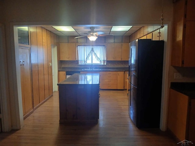 kitchen with sink, black fridge, dishwasher, a kitchen island, and ceiling fan