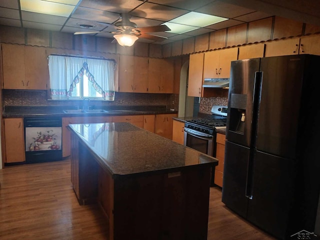 kitchen with a kitchen island, a paneled ceiling, sink, black fridge with ice dispenser, and stainless steel gas range