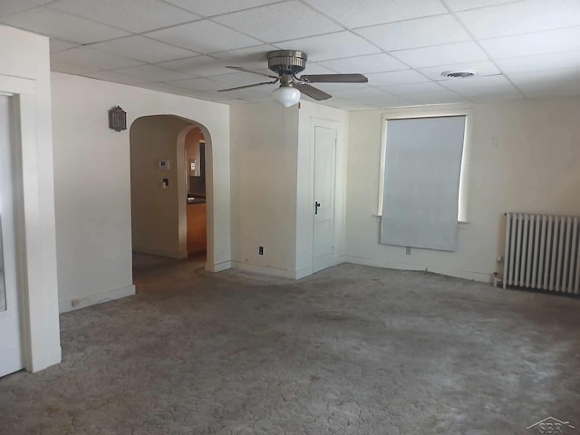 unfurnished room featuring ceiling fan, a paneled ceiling, radiator heating unit, and carpet floors