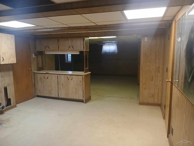 basement featuring a drop ceiling and wooden walls