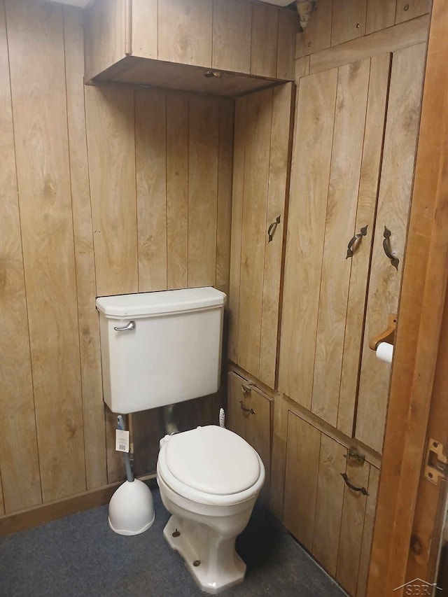 bathroom with wood walls and toilet