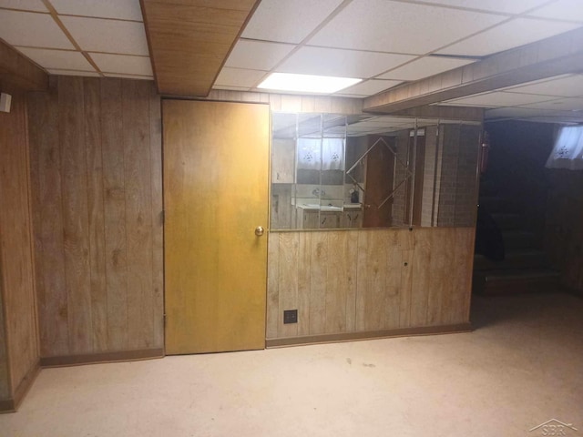 basement featuring a paneled ceiling and wooden walls