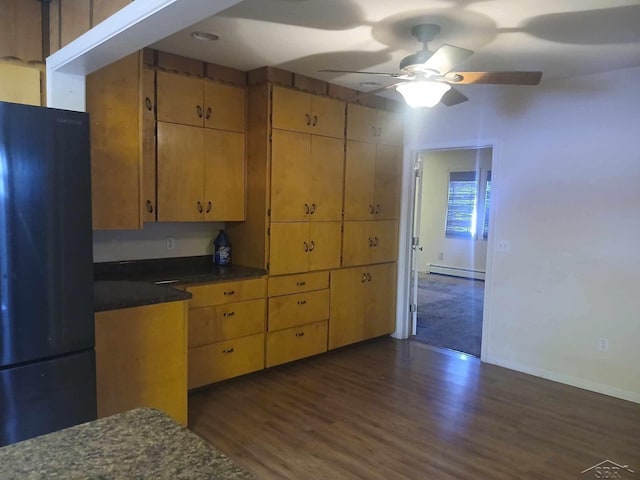 kitchen with black fridge, ceiling fan, dark hardwood / wood-style floors, and a baseboard heating unit