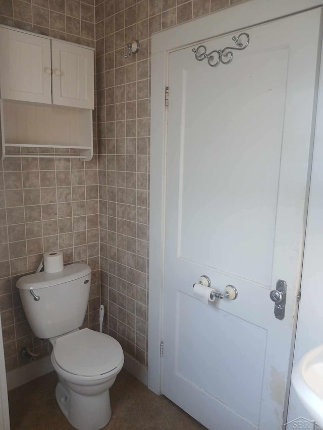 bathroom with tile walls and toilet