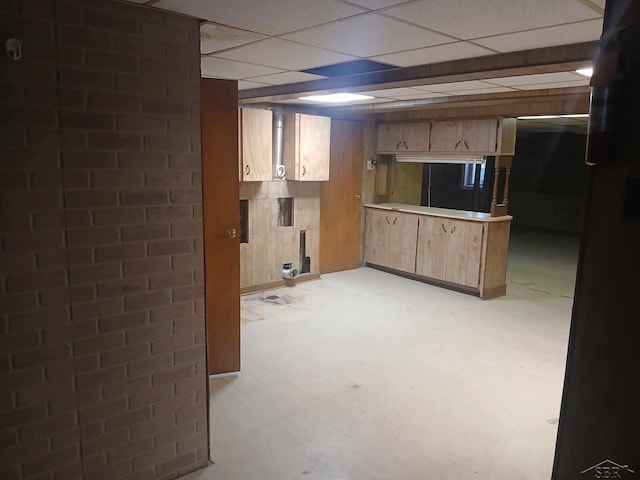 basement with a drop ceiling and wooden walls