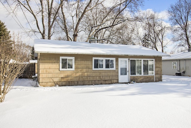 snow covered rear of property with a chimney and fence