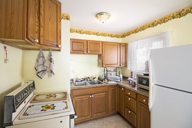 kitchen with white refrigerator, light tile patterned floors, sink, and stove