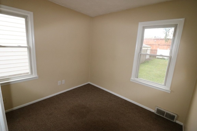 unfurnished room featuring dark carpet