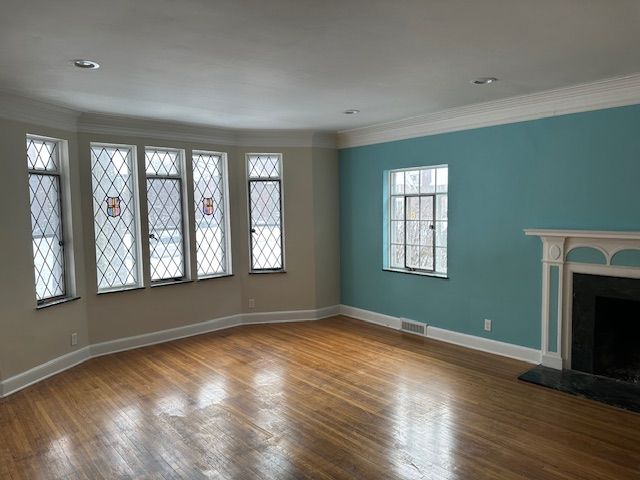 unfurnished living room featuring ornamental molding and wood-type flooring