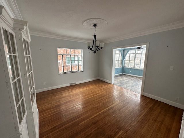 unfurnished dining area featuring ornamental molding, dark hardwood / wood-style flooring, and a notable chandelier