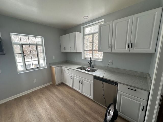 kitchen with a healthy amount of sunlight, sink, stainless steel dishwasher, and white cabinets