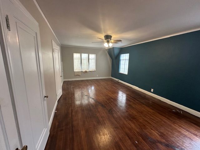 interior space featuring crown molding, dark wood-type flooring, and ceiling fan