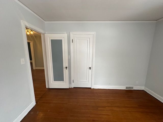 unfurnished room with dark hardwood / wood-style flooring and crown molding