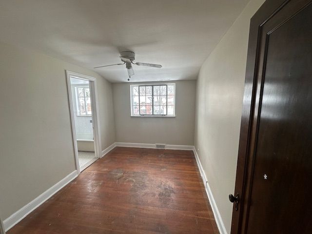 empty room featuring dark wood-type flooring and ceiling fan