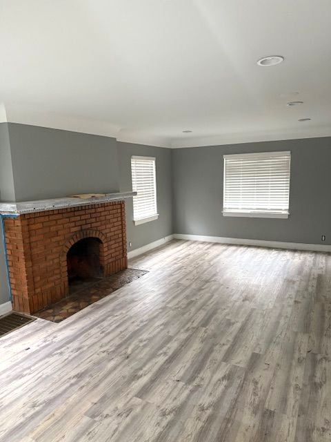 unfurnished living room with a fireplace and light hardwood / wood-style floors