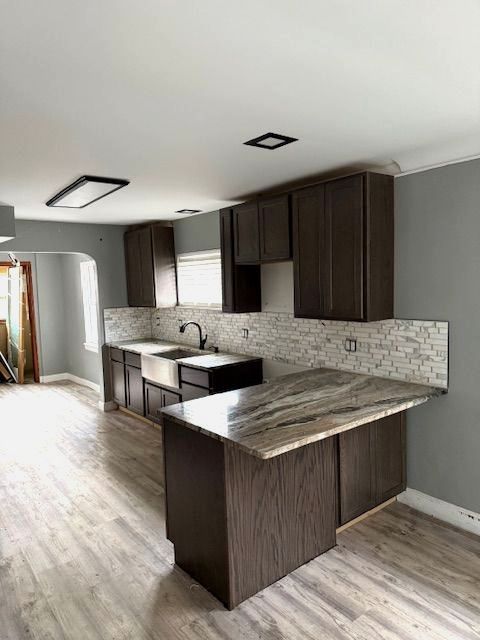 kitchen featuring dark brown cabinetry, sink, kitchen peninsula, and light wood-type flooring