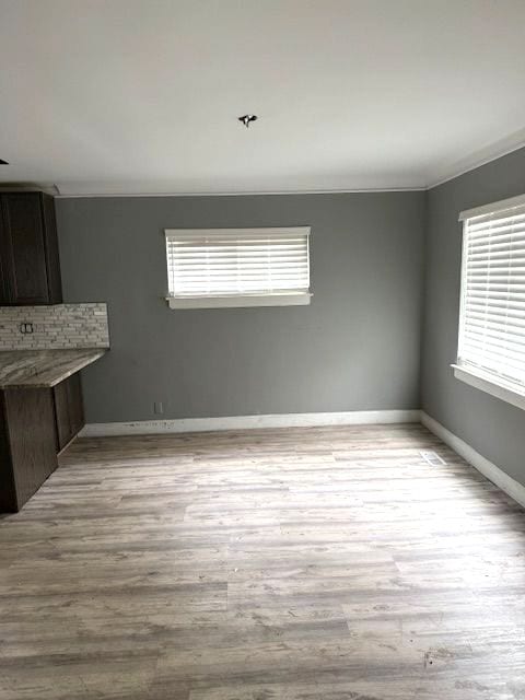 unfurnished dining area featuring ornamental molding and light wood-type flooring