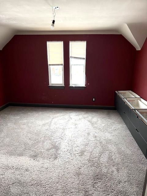 bonus room with lofted ceiling and carpet floors