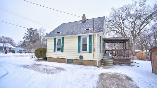 snow covered back of property featuring covered porch