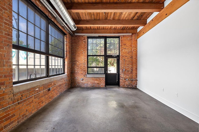 empty room featuring beamed ceiling, brick wall, plenty of natural light, and wooden ceiling