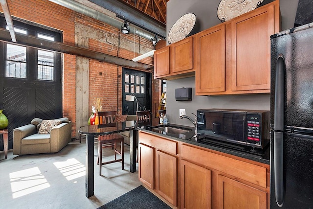 kitchen with brick wall, sink, a high ceiling, and black appliances