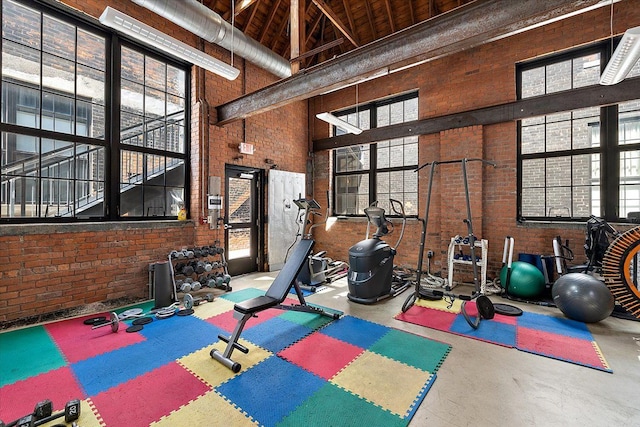 workout area featuring plenty of natural light, brick wall, and a high ceiling