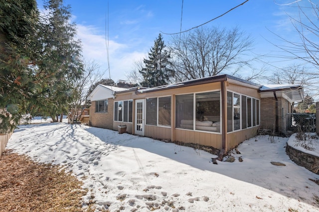 snow covered house featuring a sunroom