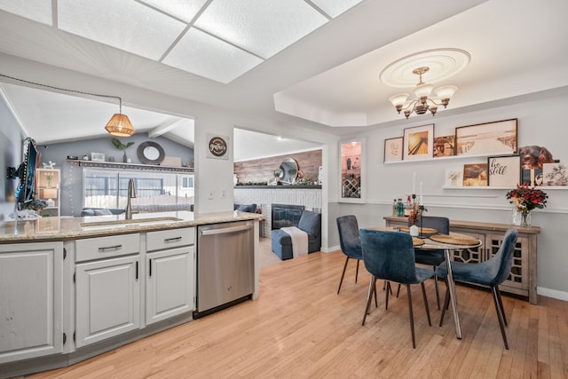 kitchen featuring a fireplace, decorative light fixtures, dishwasher, sink, and light hardwood / wood-style floors