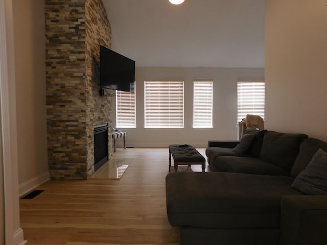 living room with a stone fireplace and light hardwood / wood-style flooring