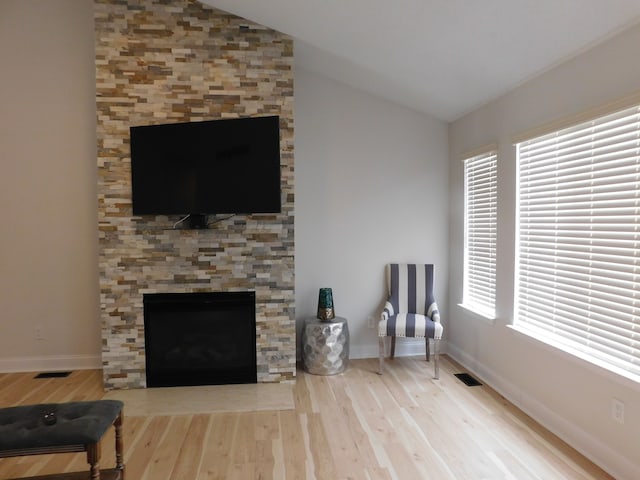 sitting room with lofted ceiling, plenty of natural light, and light hardwood / wood-style floors